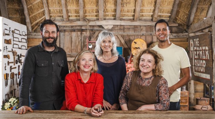 Five people smiling together in a rustic wooden setting, engaged in a friendly gathering.