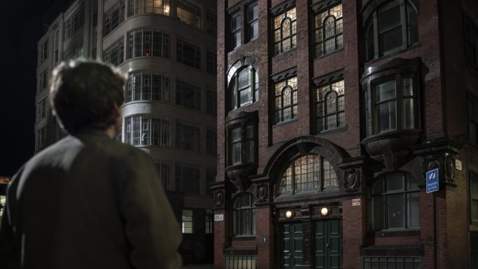 Person gazing at a beautifully lit historical building at night.